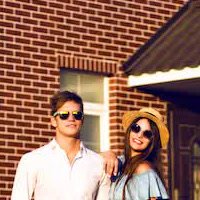 Casal sorrindo em frente à casa após a pintura