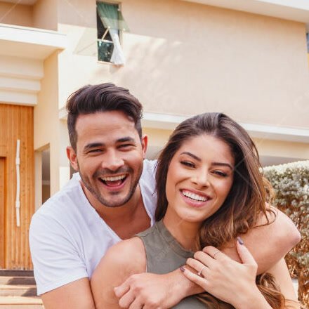Casal abraçado em frente à residência reformada
